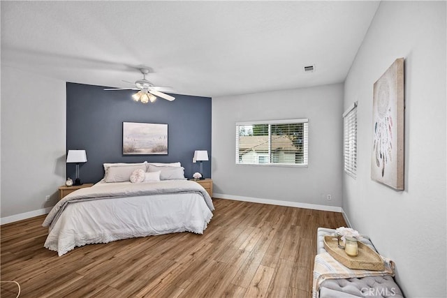 bedroom featuring ceiling fan, wood finished floors, visible vents, and baseboards