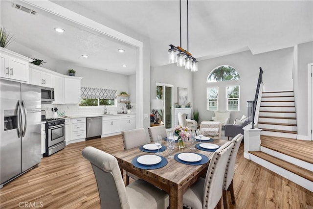 dining area with light wood-style floors, plenty of natural light, and stairs