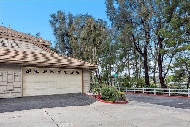 garage featuring aphalt driveway and fence