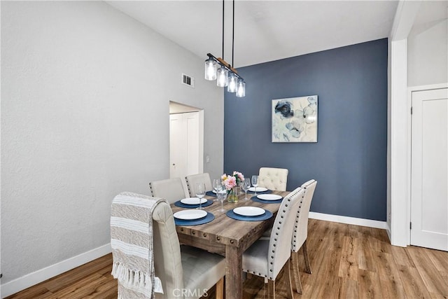 dining room featuring light wood finished floors, visible vents, and baseboards