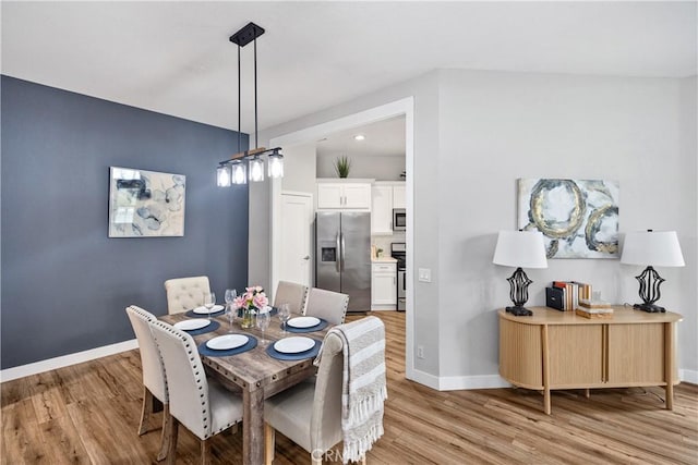 dining room featuring light wood-type flooring and baseboards