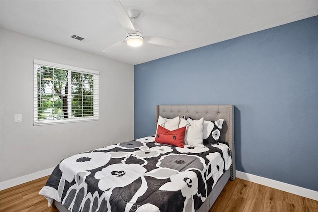 bedroom with a ceiling fan, baseboards, visible vents, and wood finished floors