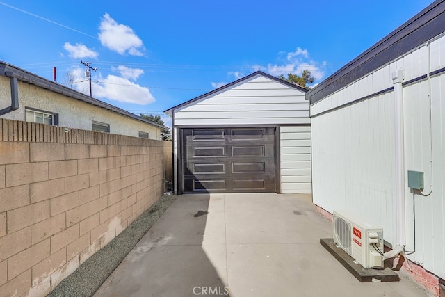 garage featuring ac unit, fence, and driveway