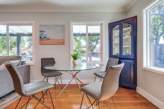 dining space featuring baseboards, light wood-type flooring, and a healthy amount of sunlight