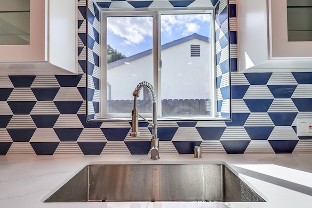 interior details featuring light stone counters, white cabinets, and a sink