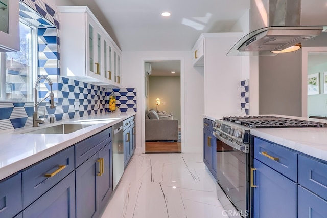 kitchen featuring stainless steel appliances, white cabinets, a sink, blue cabinets, and wall chimney exhaust hood