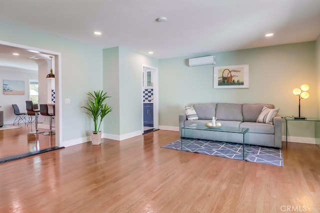 living area with light wood finished floors, baseboards, and a wall mounted air conditioner