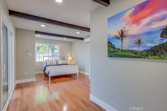 bedroom featuring baseboards, beam ceiling, and a wall mounted air conditioner