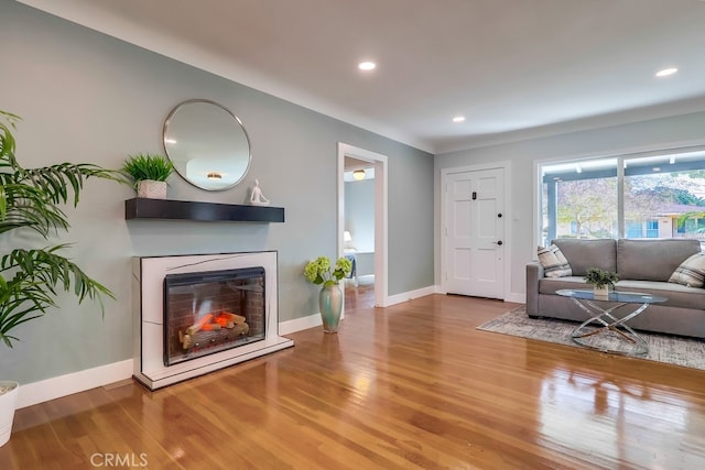 living room with recessed lighting, baseboards, wood finished floors, and a glass covered fireplace