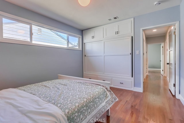 bedroom with baseboards, visible vents, and light wood finished floors