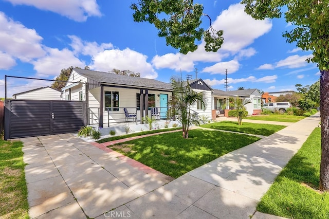 view of front of home featuring covered porch, roof with shingles, a gate, and a front yard