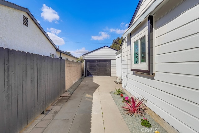 view of home's exterior with a garage, concrete driveway, fence, and an outdoor structure