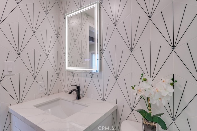 bathroom with toilet, vanity, and tile walls