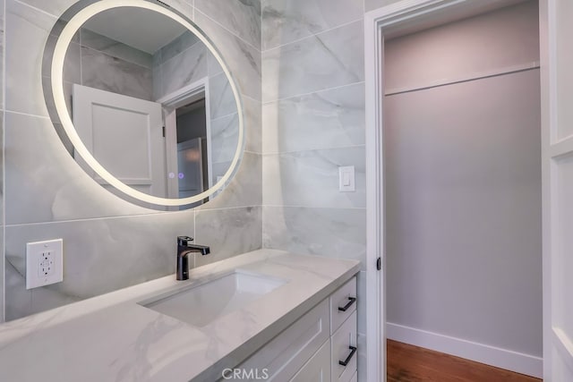 bathroom with wood finished floors, backsplash, vanity, and baseboards