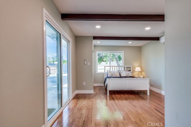 unfurnished bedroom featuring access to outside, beamed ceiling, light wood finished floors, and baseboards