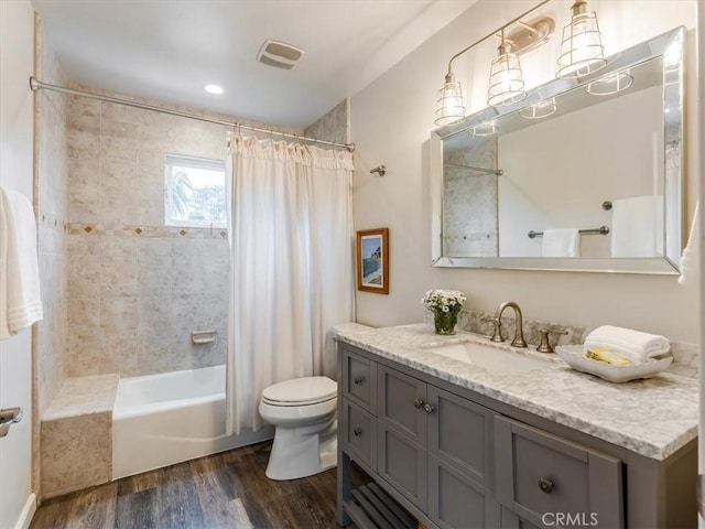 full bathroom with shower / bath combo, visible vents, toilet, wood finished floors, and vanity