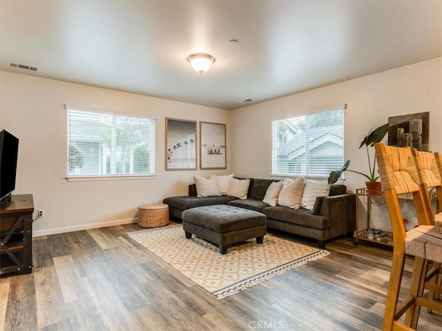 living room featuring dark wood-style flooring, visible vents, plenty of natural light, and baseboards