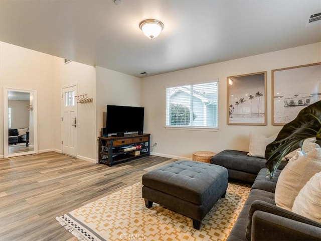 living room with visible vents, baseboards, and wood finished floors