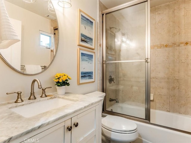 bathroom featuring toilet, bath / shower combo with glass door, and vanity