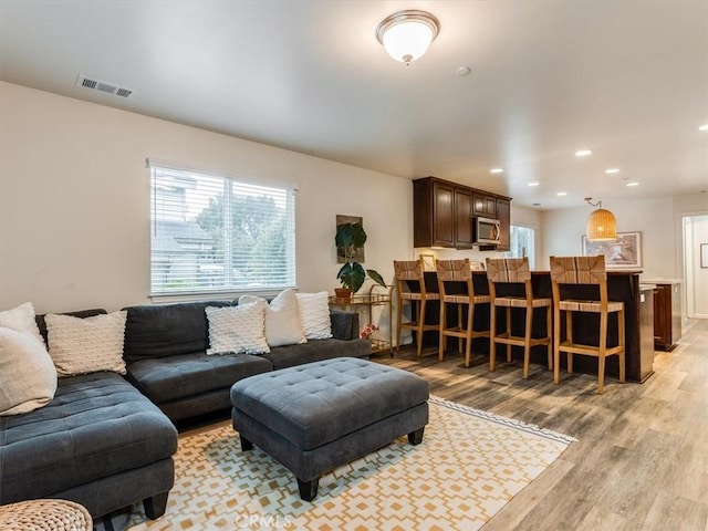 living room featuring a wealth of natural light, visible vents, light wood-style flooring, and recessed lighting