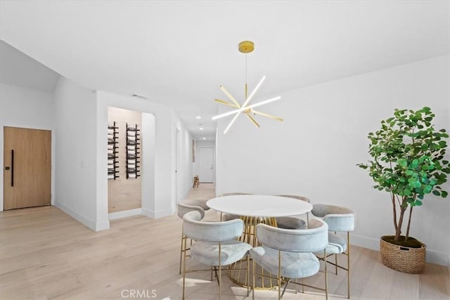 dining space featuring light wood-style flooring, baseboards, and an inviting chandelier