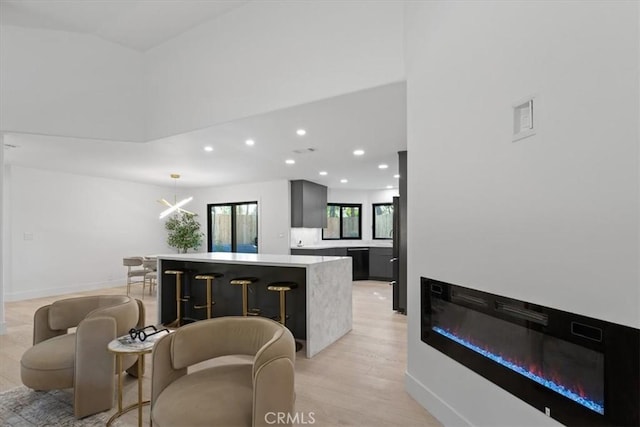 interior space with recessed lighting, baseboards, light countertops, a center island, and a glass covered fireplace