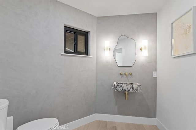 bathroom featuring baseboards, toilet, and wood finished floors