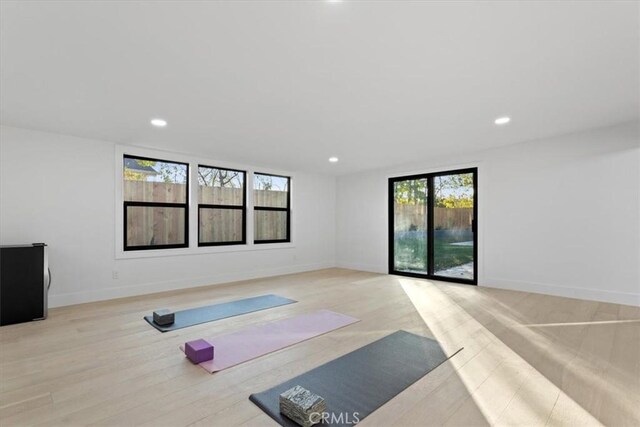 exercise room featuring baseboards, light wood-style floors, and recessed lighting