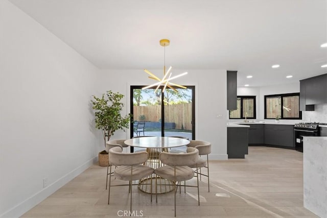 dining space with baseboards, light wood finished floors, recessed lighting, and a notable chandelier