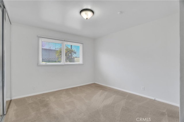 unfurnished room featuring carpet and baseboards