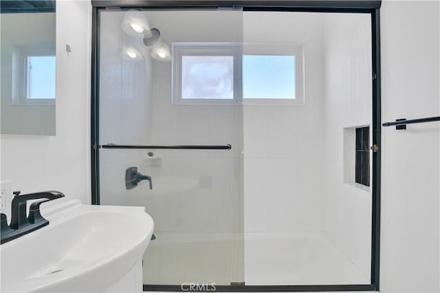 bathroom with plenty of natural light, a sink, and a walk in shower