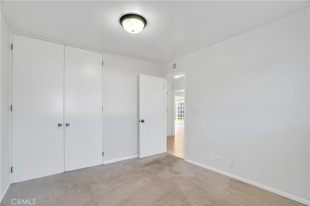 unfurnished bedroom featuring carpet, a closet, visible vents, and baseboards