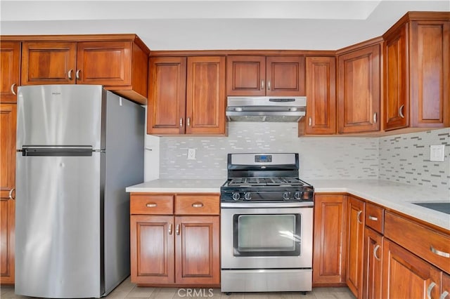 kitchen featuring brown cabinets, under cabinet range hood, appliances with stainless steel finishes, and light countertops