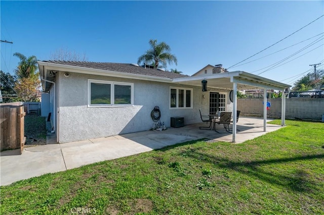 rear view of property featuring a yard, a patio, fence, and stucco siding