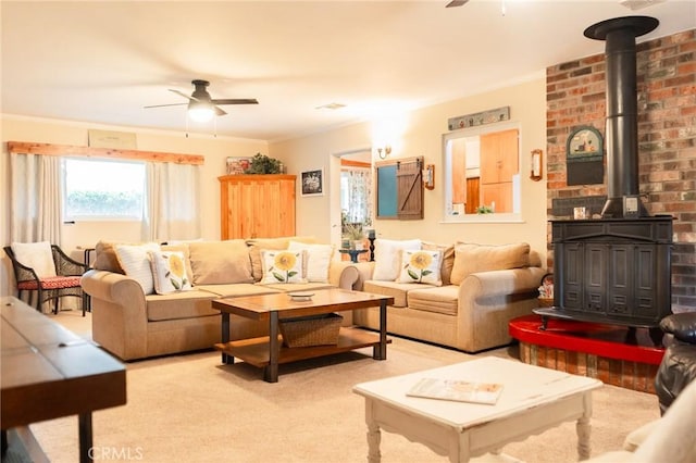 carpeted living room with a wood stove, ornamental molding, and a ceiling fan