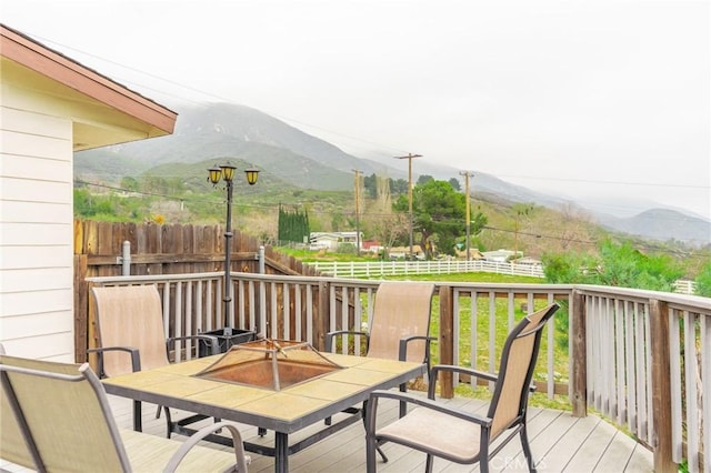 deck featuring fence, a mountain view, and outdoor dining space