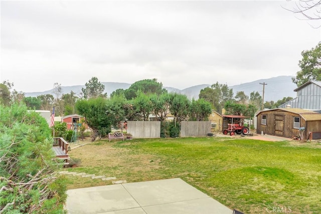 view of yard featuring a storage shed, an outdoor structure, fence, and a mountain view