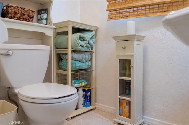 bathroom with toilet, baseboards, and tile patterned floors