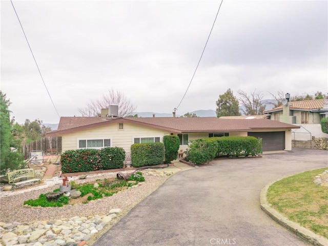 ranch-style house featuring a garage, driveway, and fence