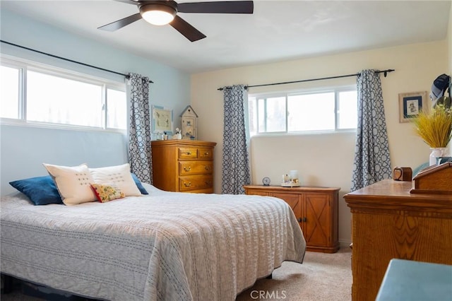 bedroom featuring light carpet, multiple windows, and a ceiling fan