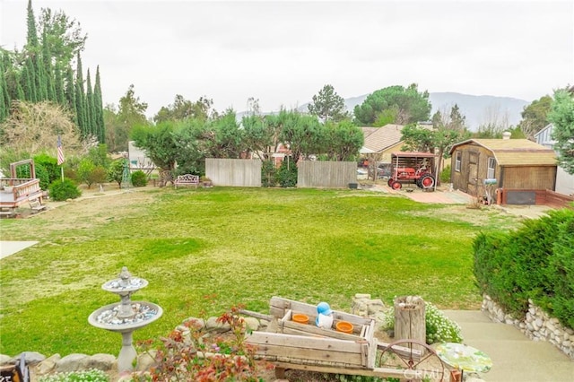 view of yard with an outbuilding, a storage unit, fence, and a mountain view