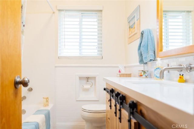 full bath with toilet, shower / bath combo with shower curtain, and vanity