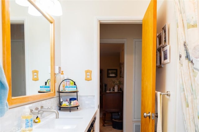 bathroom featuring visible vents, backsplash, and vanity