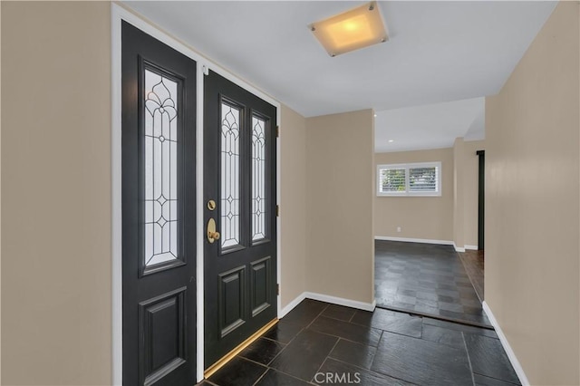 entryway with stone tile flooring and baseboards