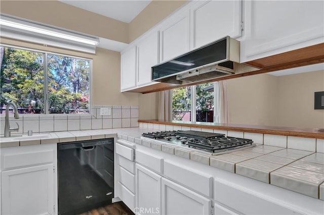 kitchen with tile countertops, stainless steel gas stovetop, white cabinetry, a sink, and dishwasher