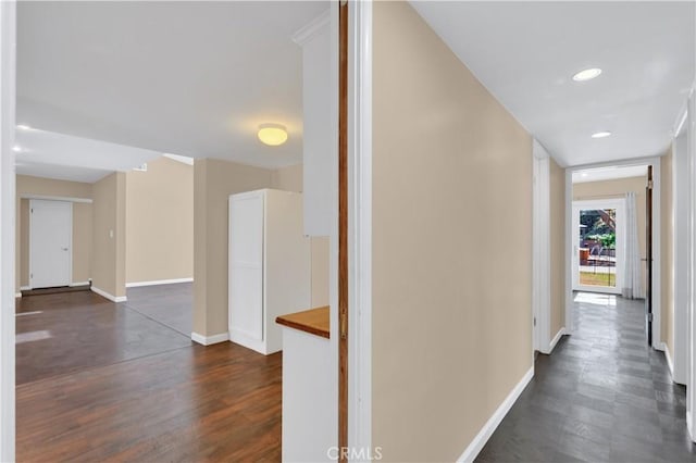 hallway featuring dark wood-style flooring, recessed lighting, and baseboards