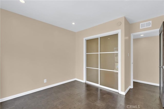 empty room with baseboards, visible vents, wood finished floors, and recessed lighting