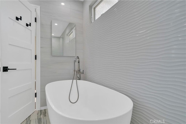 bathroom featuring tile walls and a freestanding bath