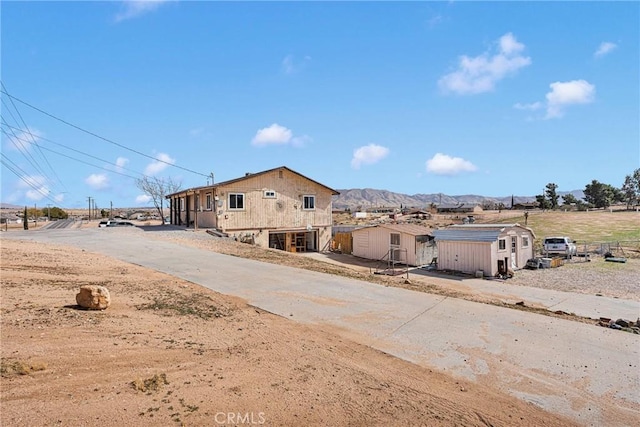 view of front of home with an outdoor structure, a storage shed, and a mountain view