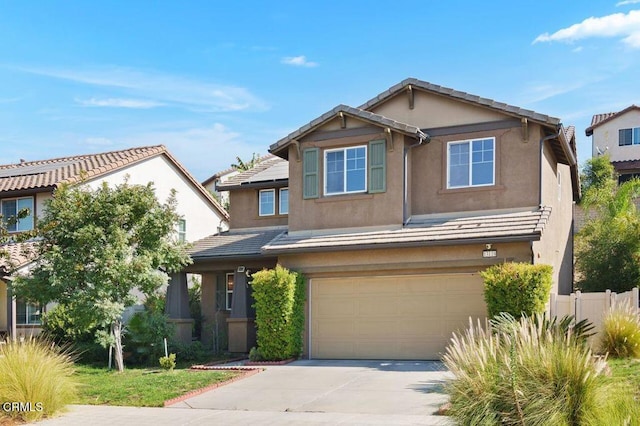 view of front facade with an attached garage, fence, a tile roof, concrete driveway, and stucco siding